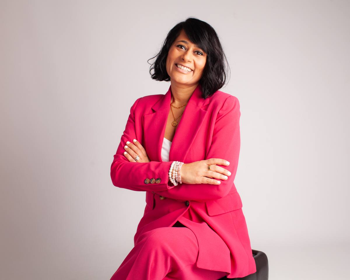 An image of Dr Aditi Bhalla in a professional bright pink suit, seated and smiling