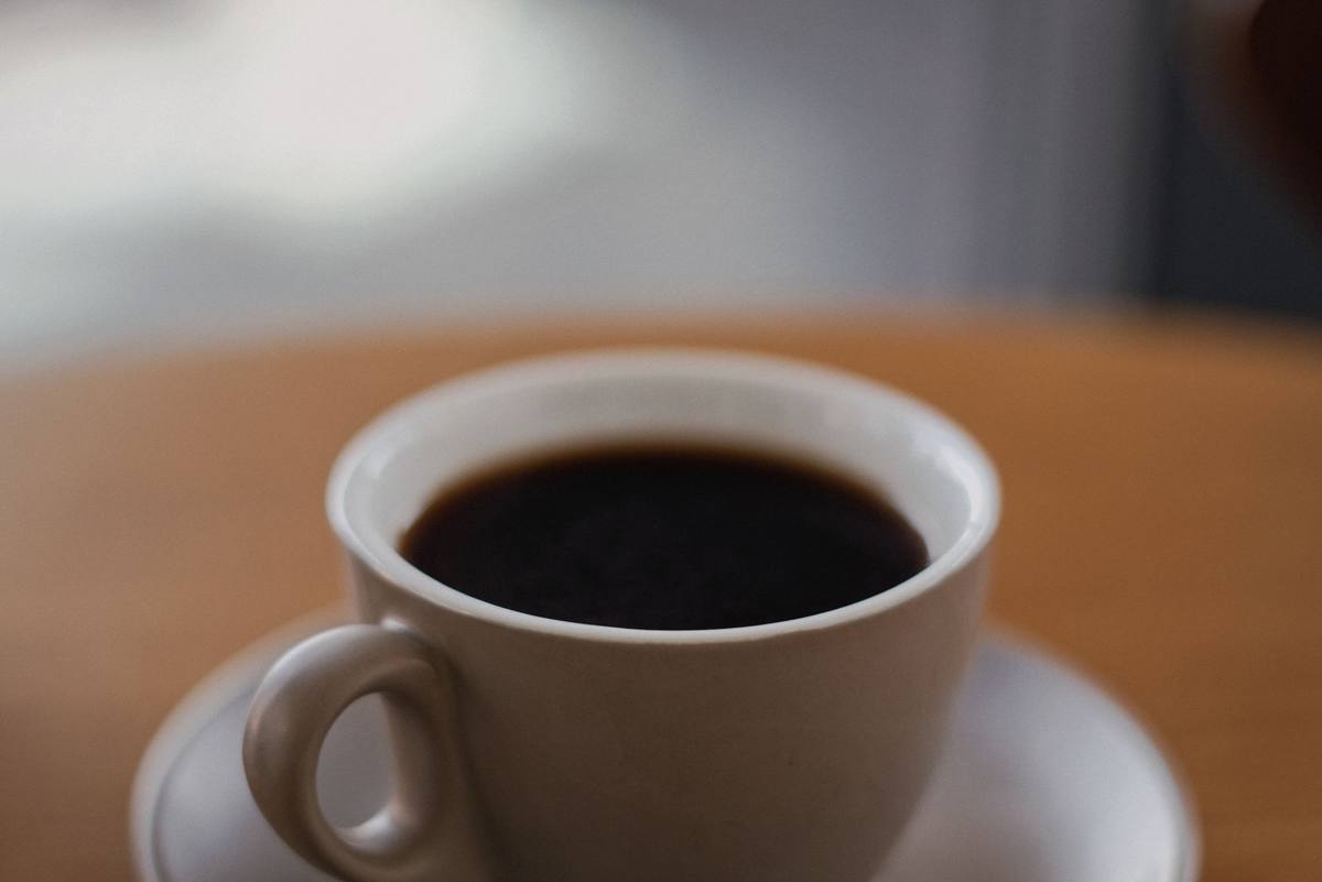 A cup of black coffee sitting on a wooden table