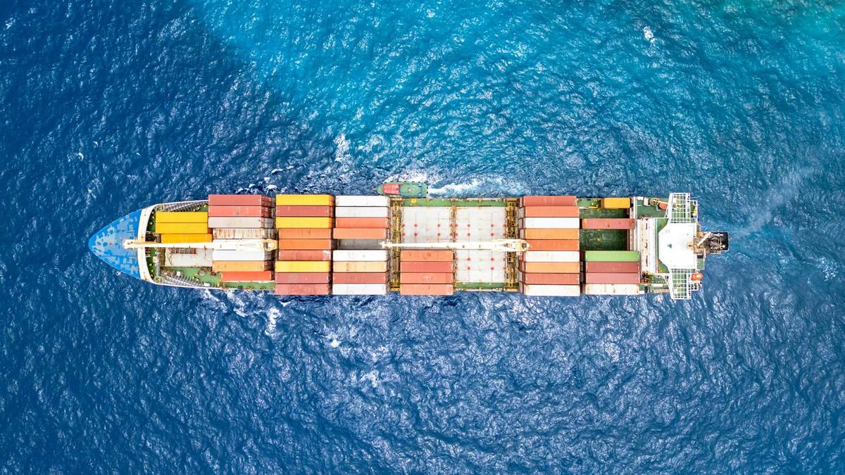 Aerial view of a container ship loaded with coloured containers crossing deep blue sea