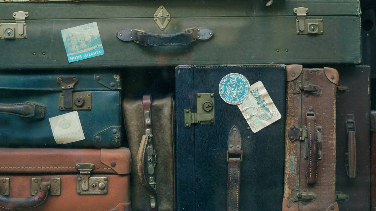 A stack of worn vintage suitcases with old travel labels on them