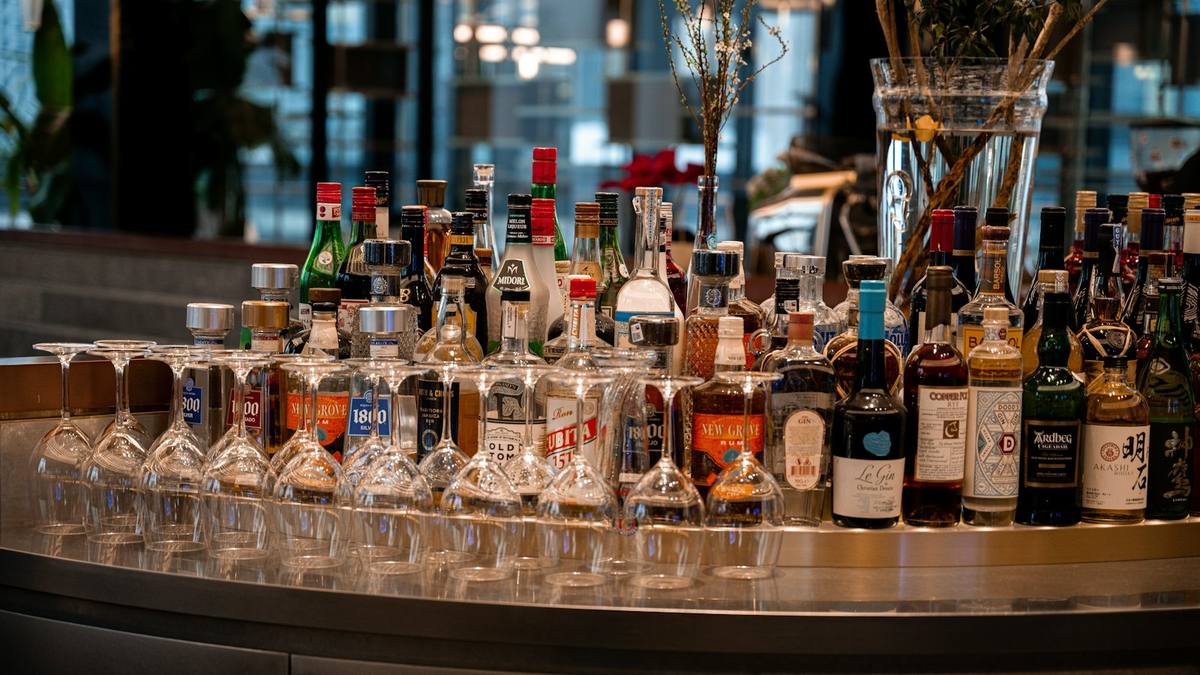 Rows of spirit bottles and upturned glasses on a bar counter