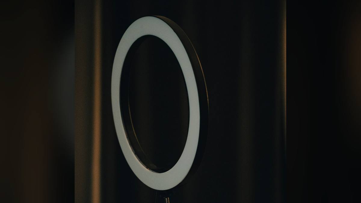 A ring light on a stand glowing in a dark room