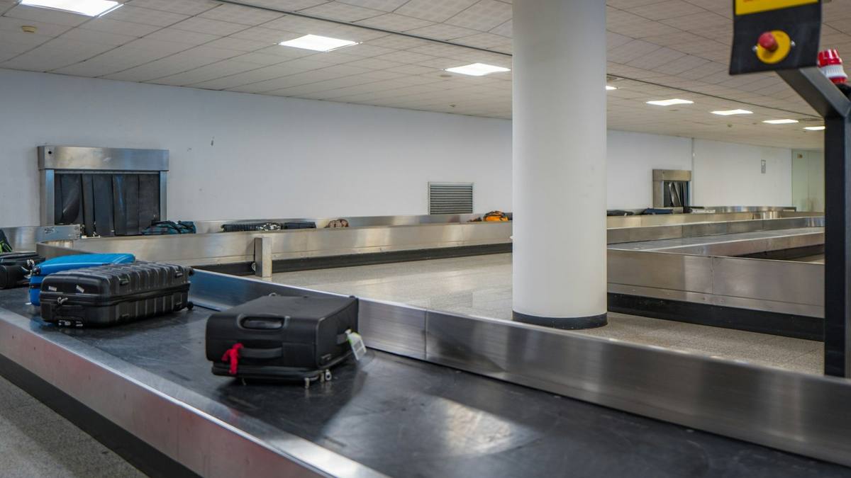 Two suitcases on an empty airport baggage carousel beside a white pillar