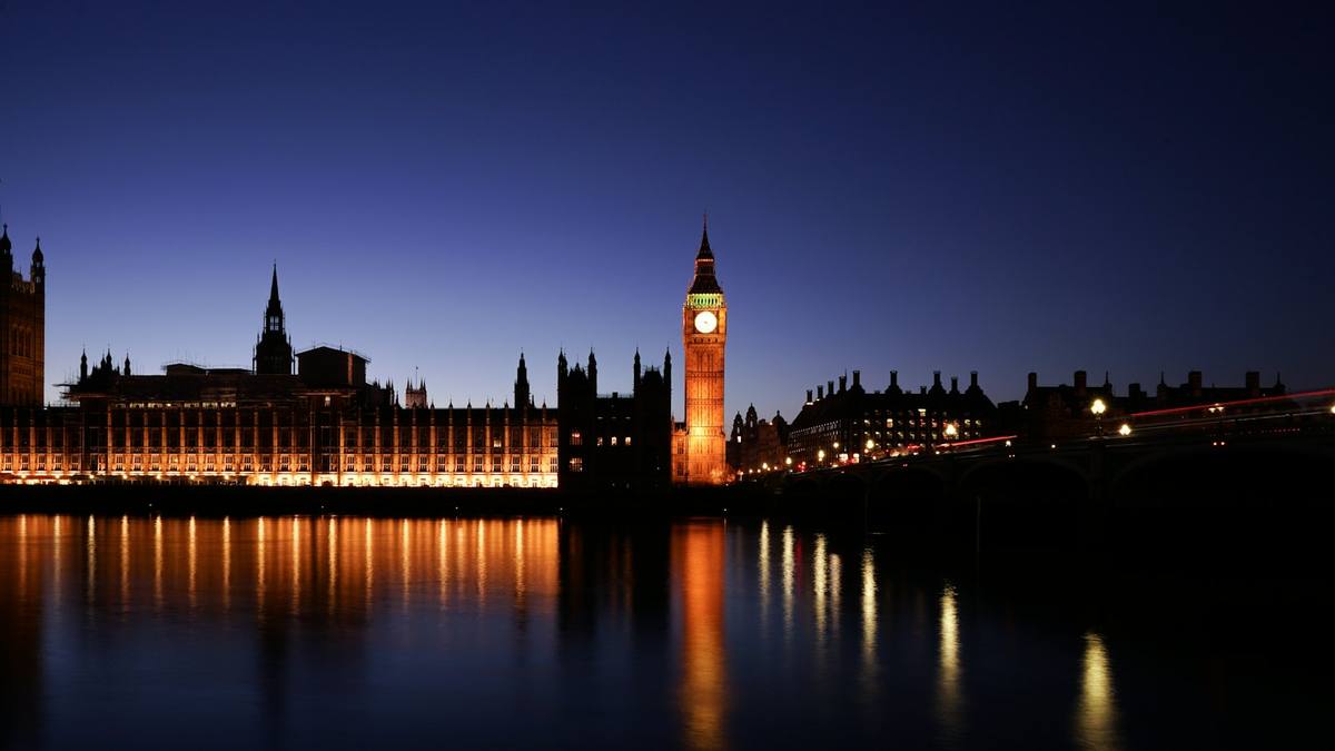 The Elizabeth Tower clock lit up beside the Houses of Parliament at night