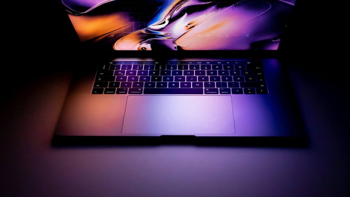An open laptop glowing on a table in a dark room