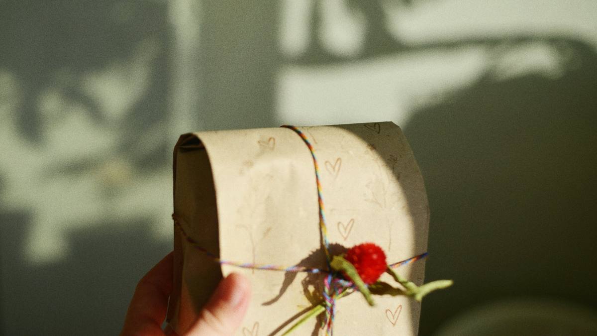 A hand holding a small paper parcel tied with string