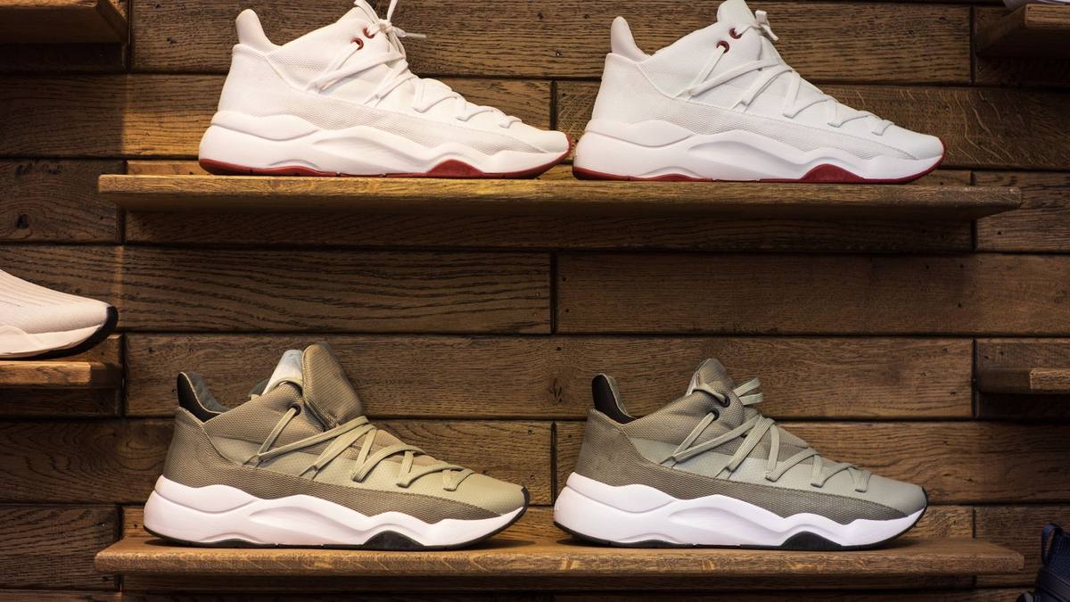 Pairs of white and grey trainers lined up on wooden shelves