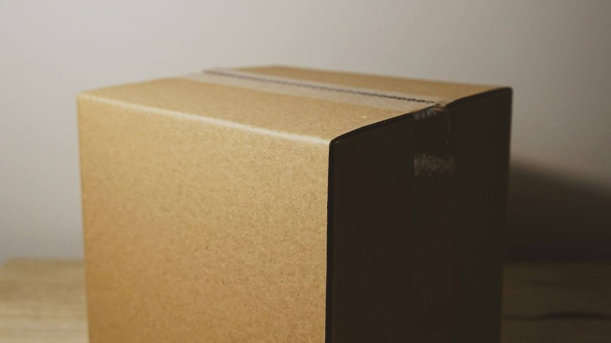 A plain cardboard box on a wooden table against a pale wall