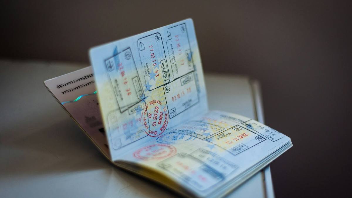 An open passport with entry stamps on its pages, resting on a table