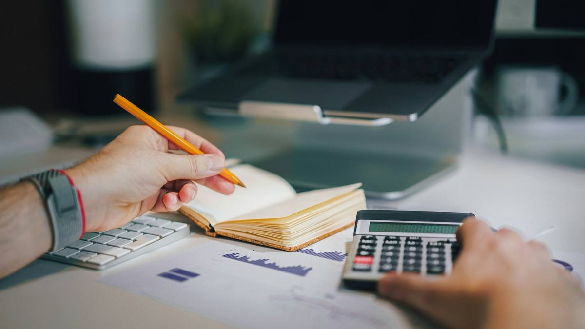 A person at a desk working with a calculator and a notebook