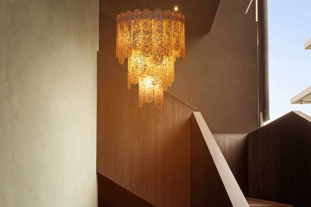Spark & Bell’s “Seraphín” chandelier located in a modern hallway/lobby.