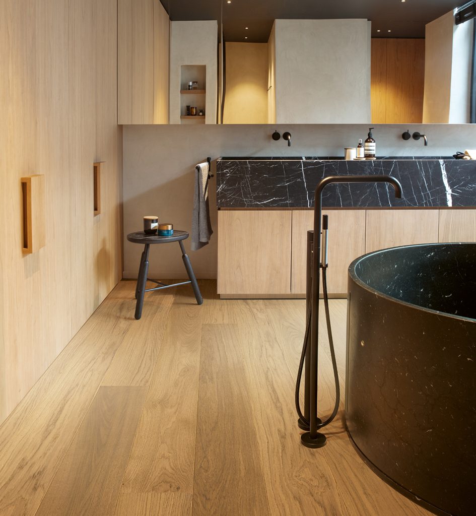 A modern and contemporary bathroom featuring a soft honey-toned floor from Quick-Step.